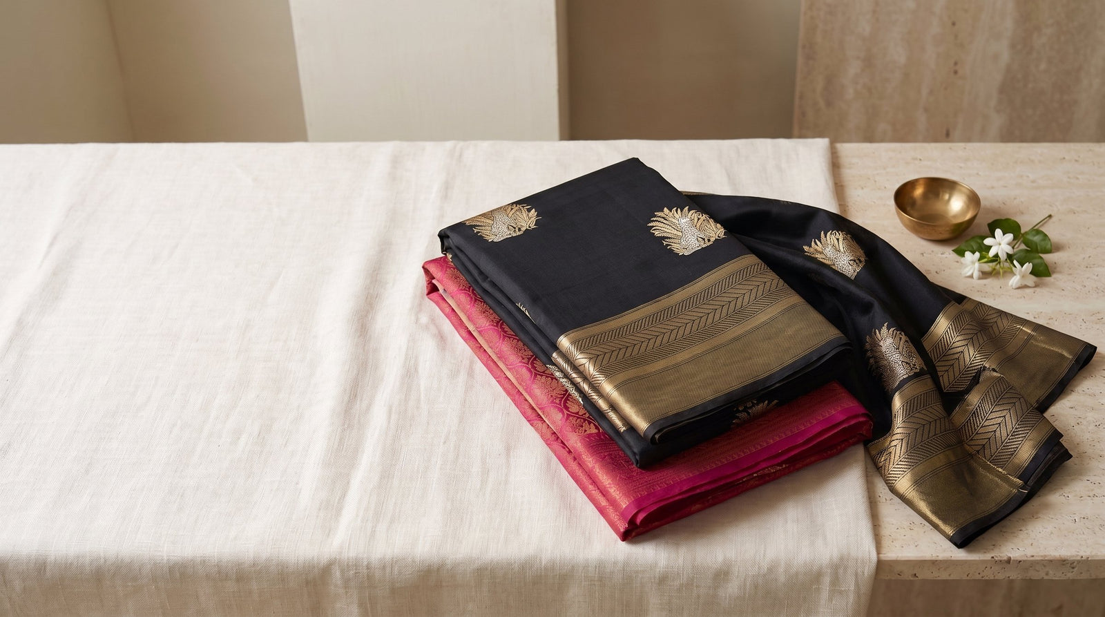 Folded Banarasi silk sarees with gold zari on ivory linen